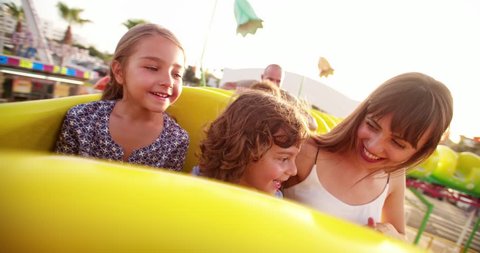 Multi-ethnic children on a funfair roller coaster ride with parents on summer holidays