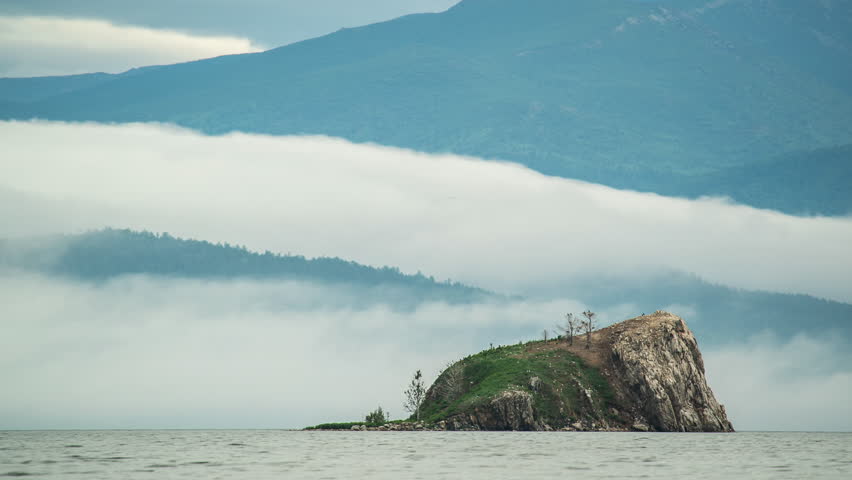 time lapse video of fast clouds above water of lake and rocky island. mountain and lake landscape. nature