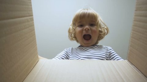 A little boy looks in the box, is surprised and happy to receive a surprise. The child opened a box with a gift. Slow Motion.