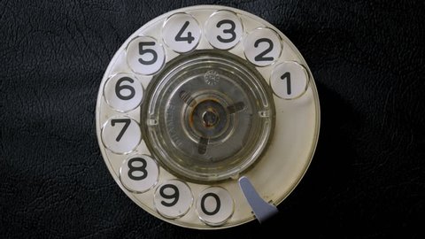 Dialing on an old rotary style telephone. Close-up view.
