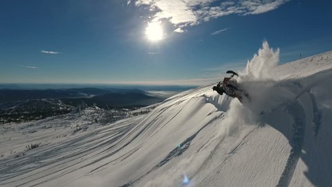 man rolling around and jumping on a snowmobile. Slow Motion Aerial.
