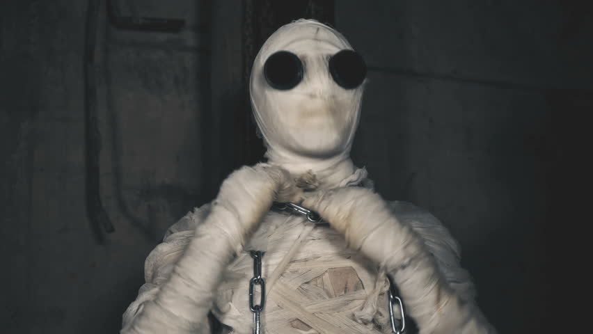 people being in bandages in a dark, abandoned building trying to break the chains wrapped around the neck