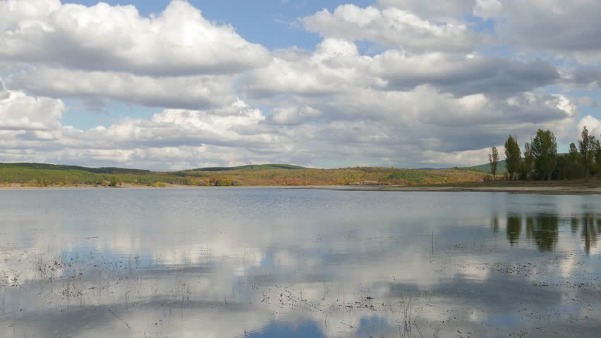 White clouds over mountain lake in autumn day / Reflection of white clouds in mountain lake 