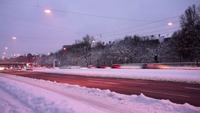 Timelapse video of a snow covered road in winter landscape at dusk, with passing cars and people