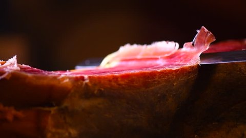 Jamon serrano. Traditional Spanish ham on black close up. Slicing Hamon iberico. Prosciutto close up. 4K UHD video 3840x2160 
