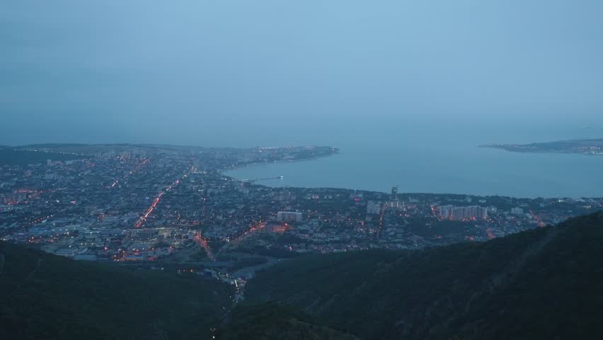 Timelaps top view from mountain of city standing on sea shore during dusk