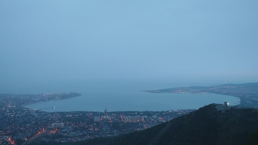 Timelaps top view from mountain of city standing on sea shore during dusk