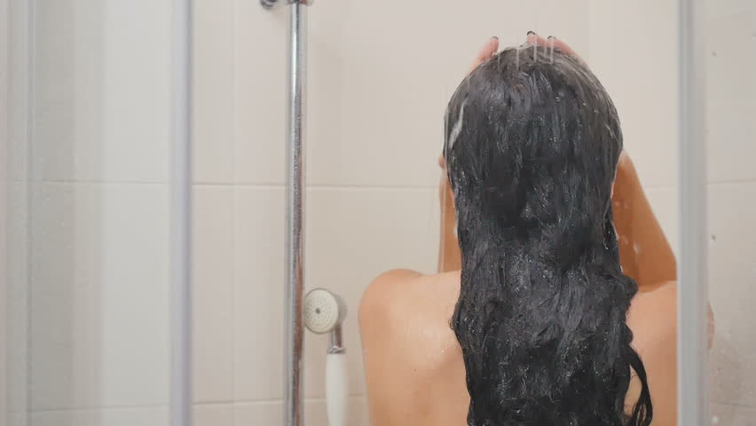 Dark-haired coquette washes her head in the bathroom