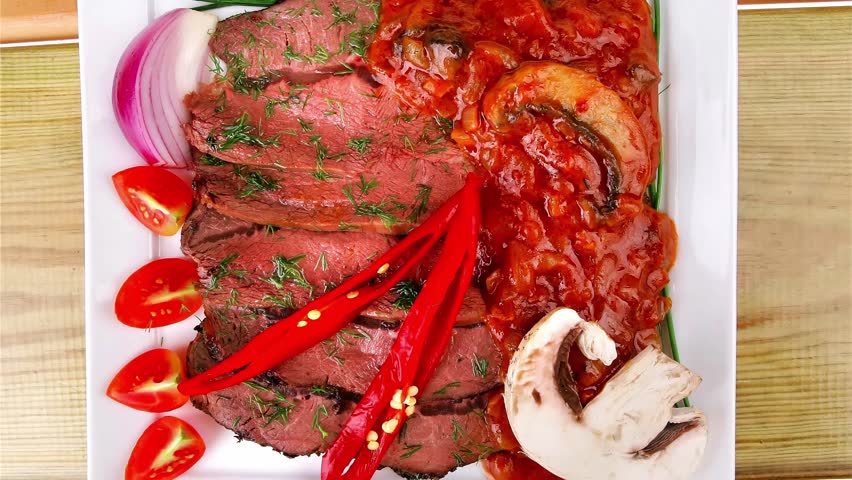 beef on plate with vegetables over wooden table