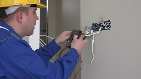 Professional electrician man using special tool to check wall socket voltage. Static shot. 4K UHD
