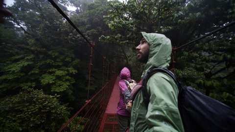 Couple walking hand by hand on hanging bridge through rain forest, national park Monteverde, Costa Rica