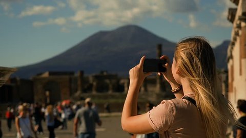 Pompeii, Italy Tourism. UNESCO World Heritage Site. Young Woman Exploring Europe.Tourist Woman Exploring Pompeii While Traveling In Italy. Tourist Taking Photograph Of Pompeii Ruins. Volcano Vesuvius