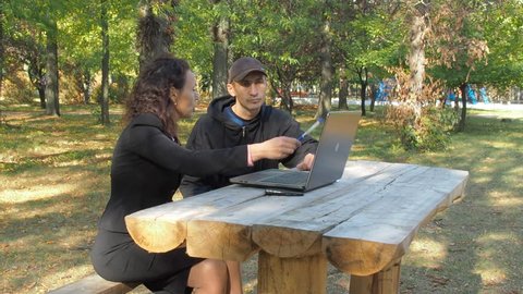 A business woman meets a customer in a park. Discussion of the project.