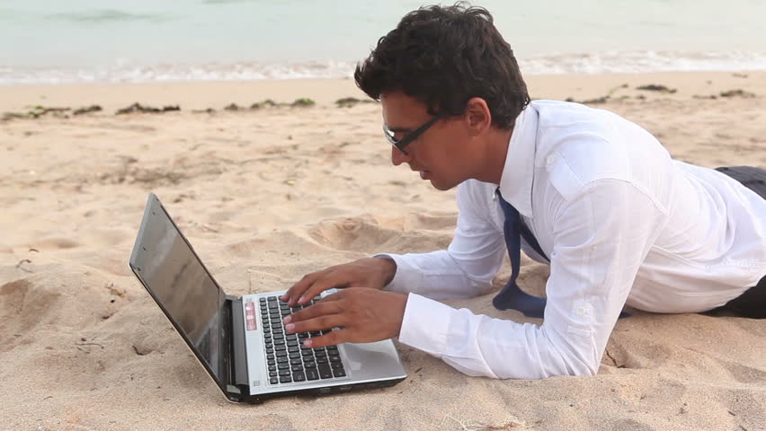 Confident businessman working at beach while summer vacation