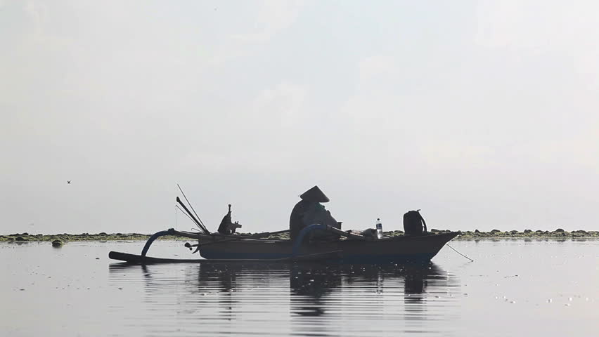 Indonesian man sitting on boat and fishing