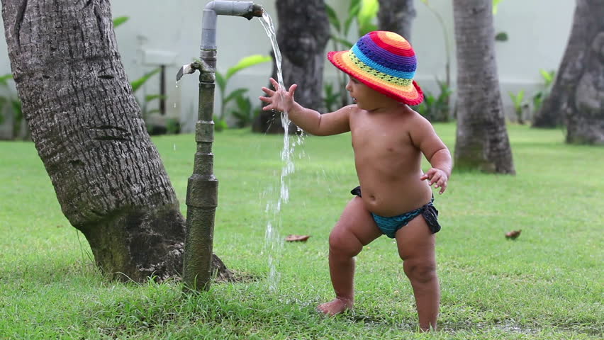 Happy beautiful girl playing with water in garden