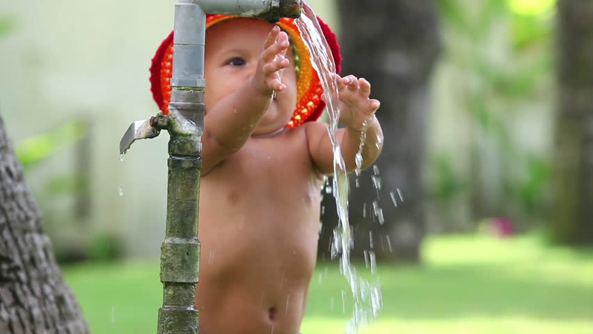 Cute small girl in hat playing with water