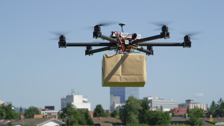 CLOSE UP: UAV drone delivery. Multicopter flying big brown package into city. Drone delivering post package to your home. Futuristic shipment by helicopter drone. Multirotor logistics and transport. Royalty-Free Stock Footage #31829827