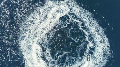 Aerial Top Down View Shot of a Person Jet Skiing in Circles. Beautiful Blue Oceanic Waters and Sun is Shining. Shot on Phantom 4K UHD Camera.