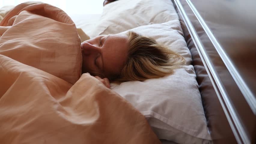 Sleepy woman waking up in bed in the morning and does not want to get out of bed. not a good morning. 4k, slow-motion shooting, copy space Royalty-Free Stock Footage #31837840