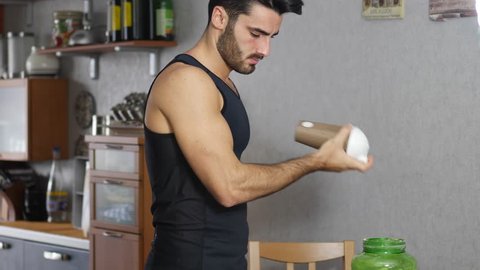 Young athletic man drinking a healthy smoothie drink or a protein shake from blender or shaker