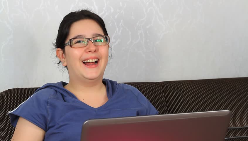 Portrait of laughing child using laptop computer, looking at camera happily
