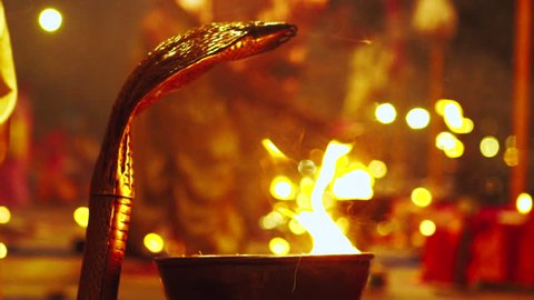 Graded & ungraded: Rose petals placed on gold religious snake head during Hindu ceremony at Ganges River celebration with candle lit prayer at night - Slow motion close up