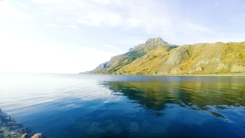 The man dives into the water against the background of the mountains