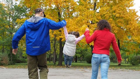 Happy family in autumn park. Parents with the child walk in the park.