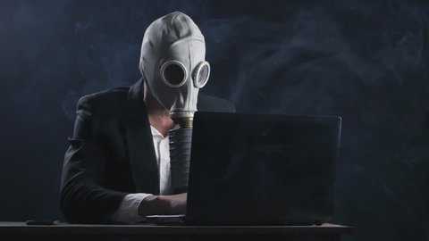 businessman in gas mask working at laptop in office in smoke