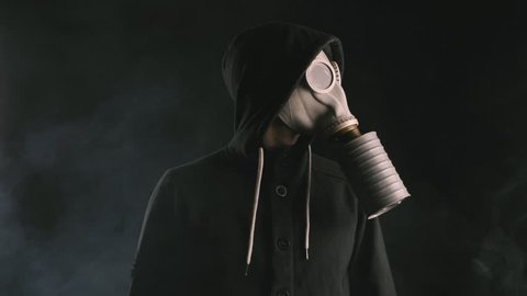 man in a gas mask in smoke in a dark room