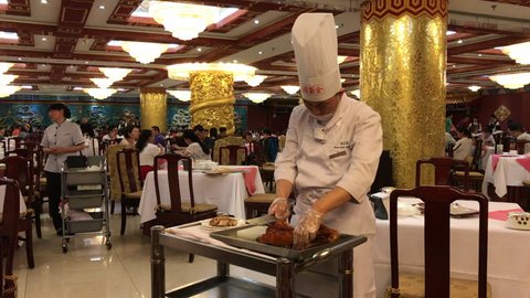 Beijing, China - May 21, 2017: Chef slicing the Peking roast duck in a restaurant. The dish is considered to be the delicious speciality of the region.