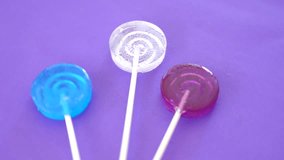 colored lollipops on a purple background rotate. 4k.