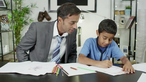 A father helps his young son while the boy is doing his homework: film stockowy