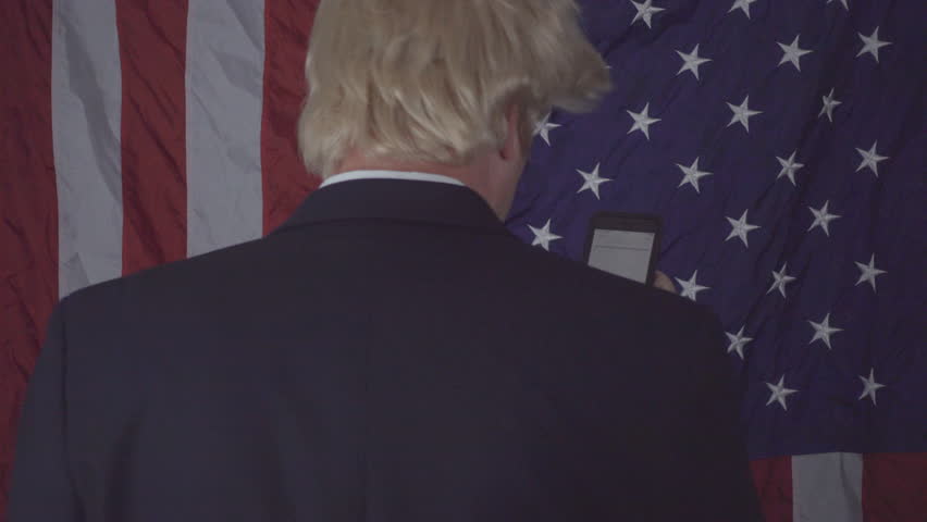 President Trump look alike tweeting on his phone with American flag