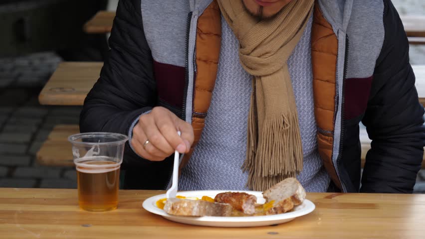 Young Man Eating Snacks And Sausage And Drinking Beer At Street Food Festival Market In Poland