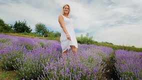 Slow motion video of happy smiling woman dancing and enjoying sun at lavender field