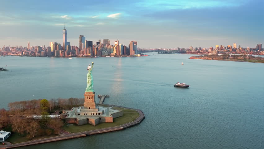 Aerial view of the Statue of Liberty at dusk. Manhattan and New Jersey skyline. New York City, United States. Shot from a helicopter. Royalty-Free Stock Footage #31885084