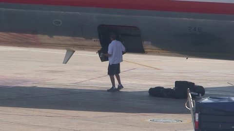 ATLANTA, GEORGIA - CIRCA 2009: airline baggage handler unloads baggage