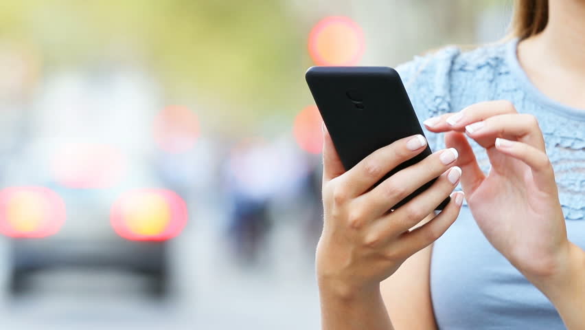 Close up of woman hands using a smart phone searching content on the street