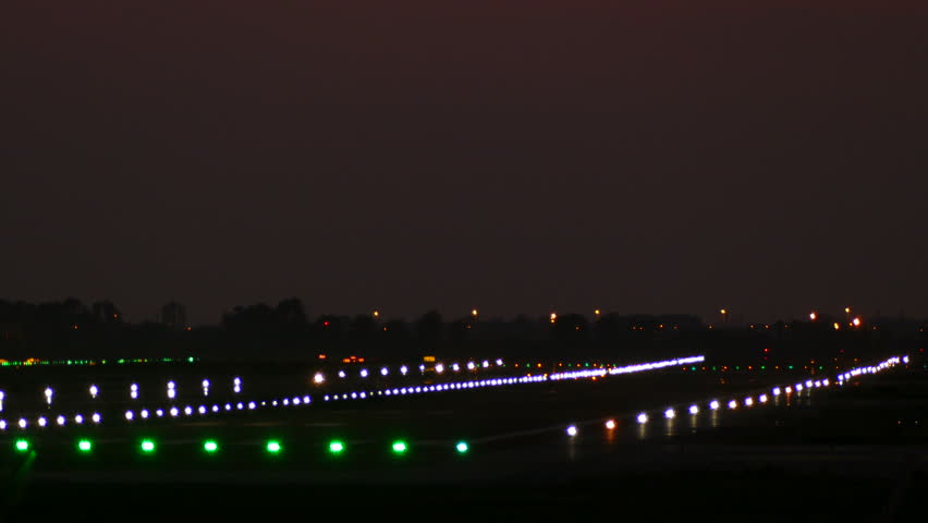 Big plane landing at Barcelona airport seen from behind at night with lit signal lights on the runway.  Royalty-Free Stock Footage #31890274