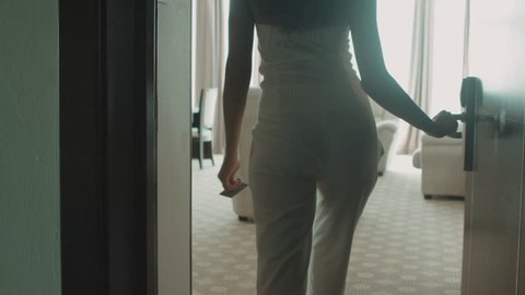 Attractive young woman in trouser suit opens the door to the hotel room