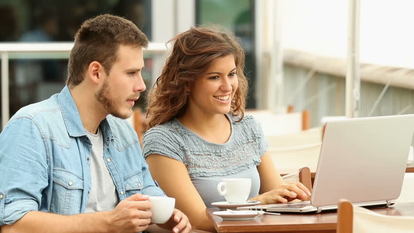 Happy couple talking about on line laptop content in a bar terrace Royalty-Free Stock Footage #31891498