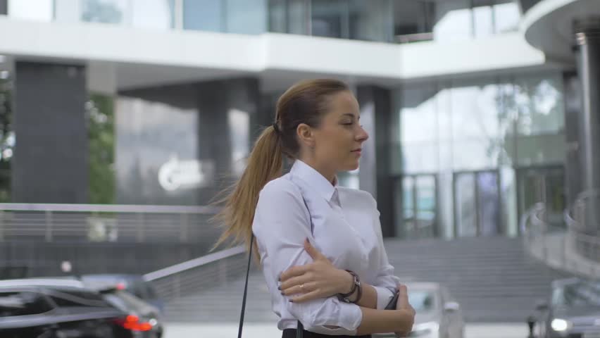 Girl walking in the city. white blouse business style. the girl freezes in the wind