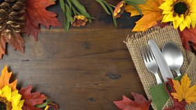 Thanksgiving theme fall leaves, flowers and rustic burlap cutlery setting and We Gather Together message overhead real time. 