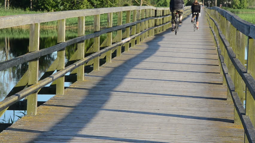 couple cyclists wooden lake bridge.