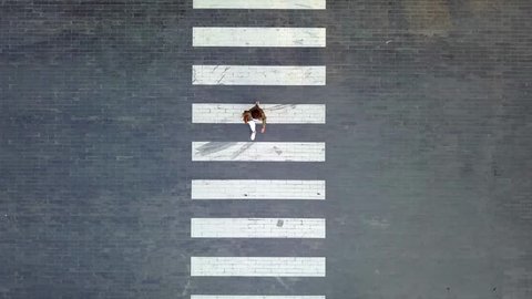 A woman crossing on crosswalk during evening day - Aerial Shot - Birdeyes angle