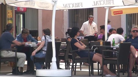 PIRAN, SLOVENIA - CIRCA 2011: People enjoy the outdoors on a cafe terrace.
