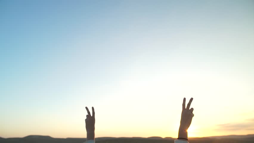 Tilt down on a young woman with her arms up in victory in a desert scenery. Success and happiness over a win or positive outcome. Freedom and carefree feeling in nature. Happy cheerful doing v sign Royalty-Free Stock Footage #31923523