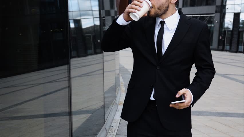 Boss talking on mobile cell phone in city wearing suit in city business district. Confident young business man talking on smartphone. Coffee break. Slow motion high-speed camera 250 fps